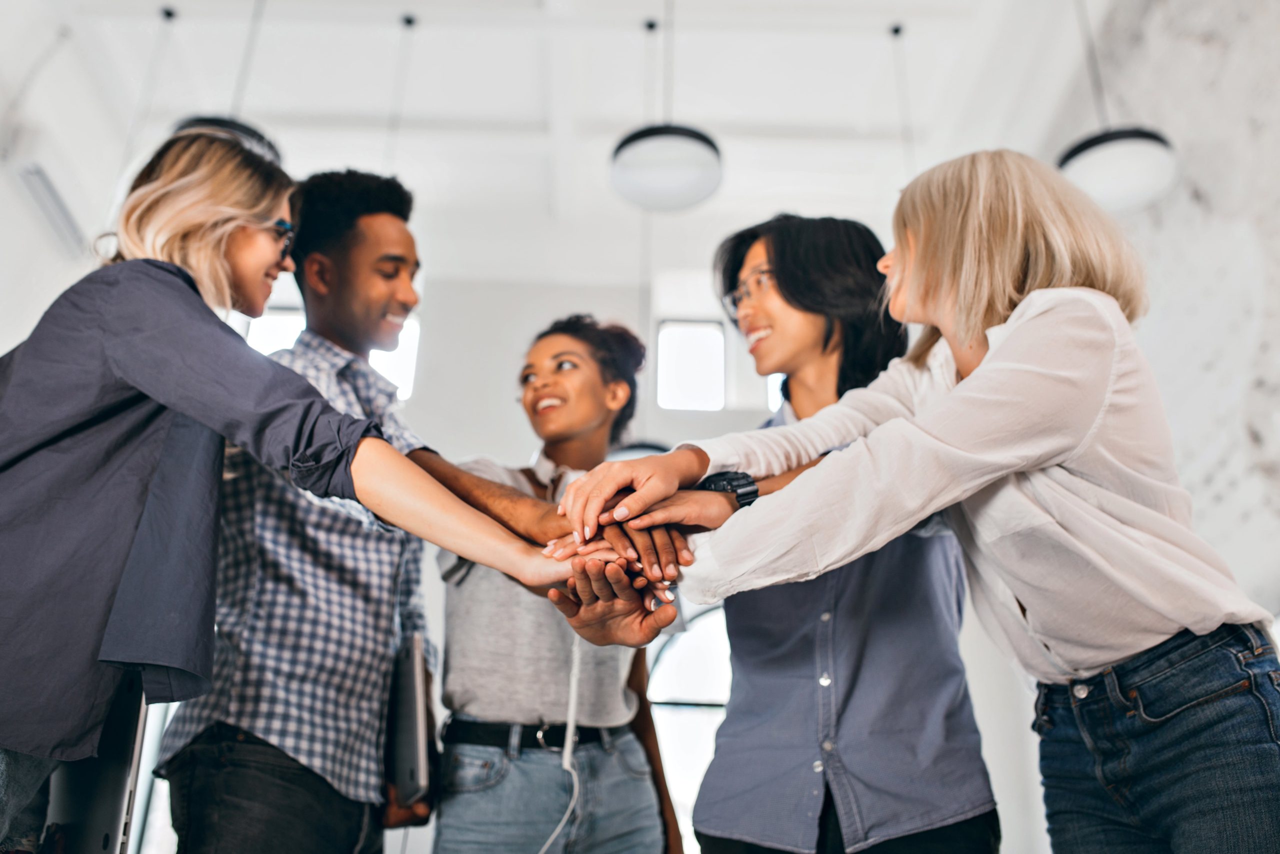 cheerful-international-students-with-happy-face-expression-going-work-together-science-project-indoor-photo-blonde-woman-trendy-blouse-holding-hands-with-coworkers-min