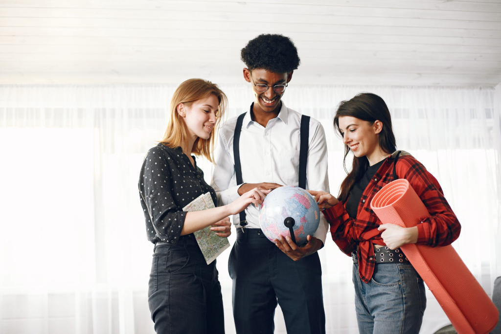 Diverse friends are going for a journey. They are planning using the globe. Bright living room.