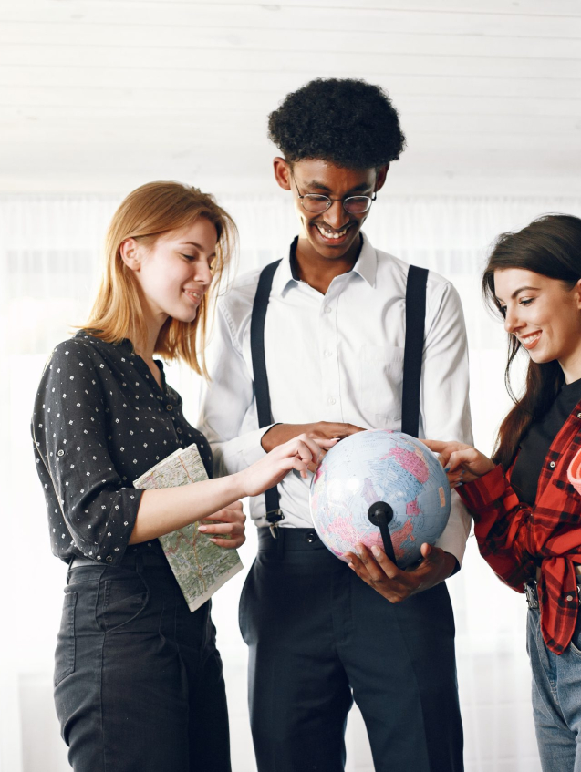 Diverse friends are going for a journey. They are planning using the globe. Bright living room.